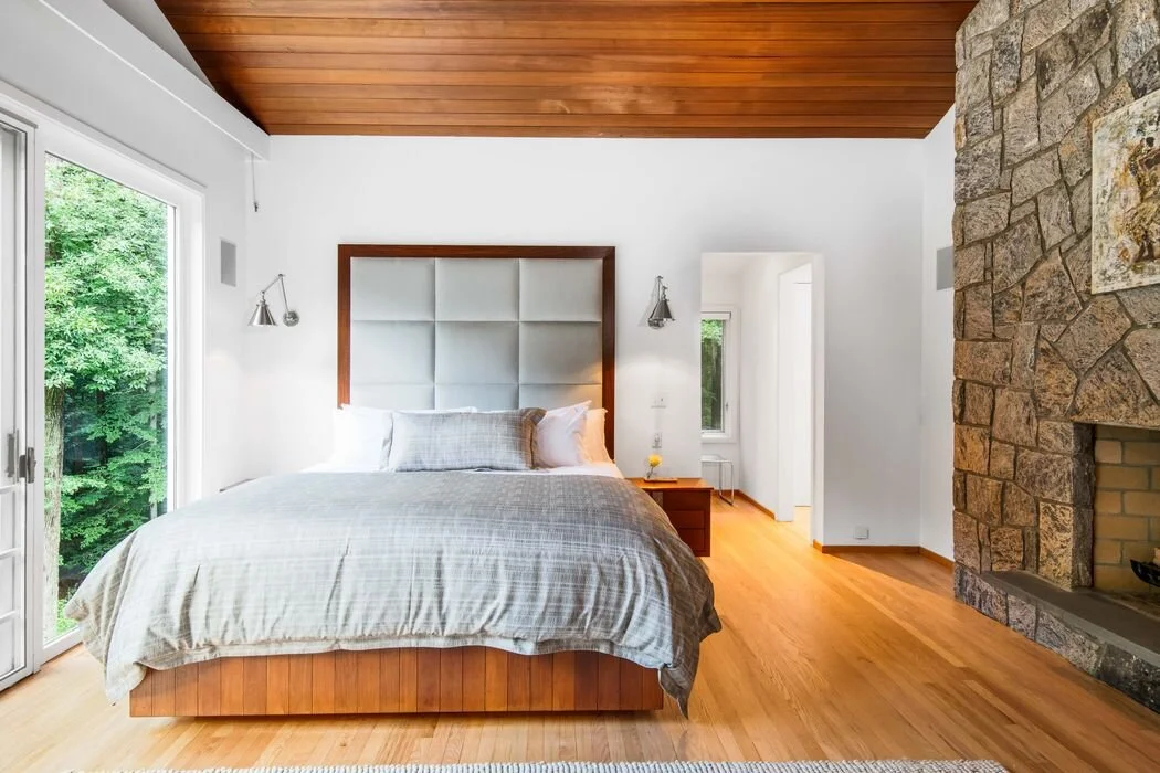 Bedroom with stone fireplace and hardwood floors